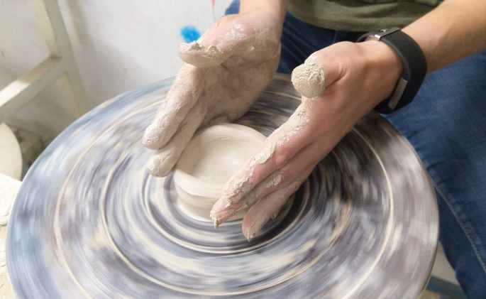 person making pottery in room